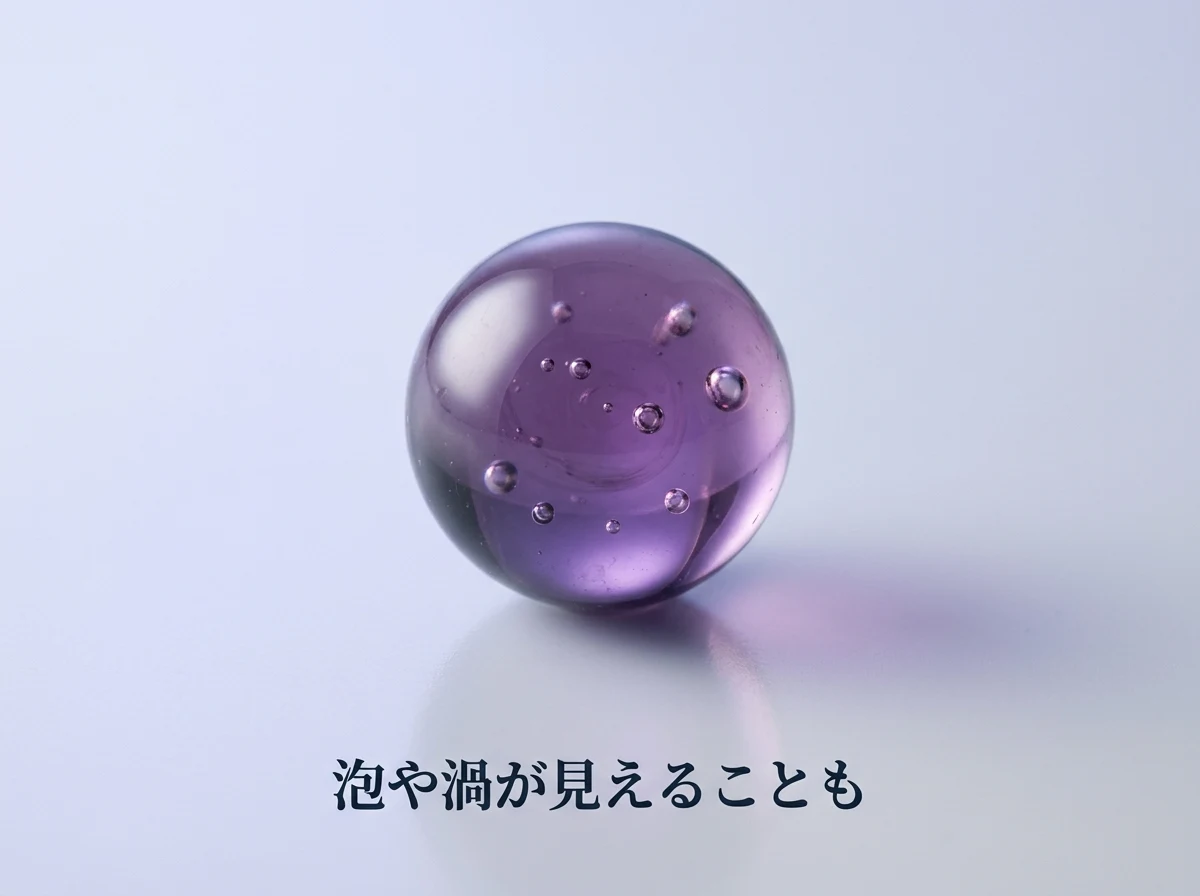 内部に丸い気泡が見えるガラスの紫色の玉