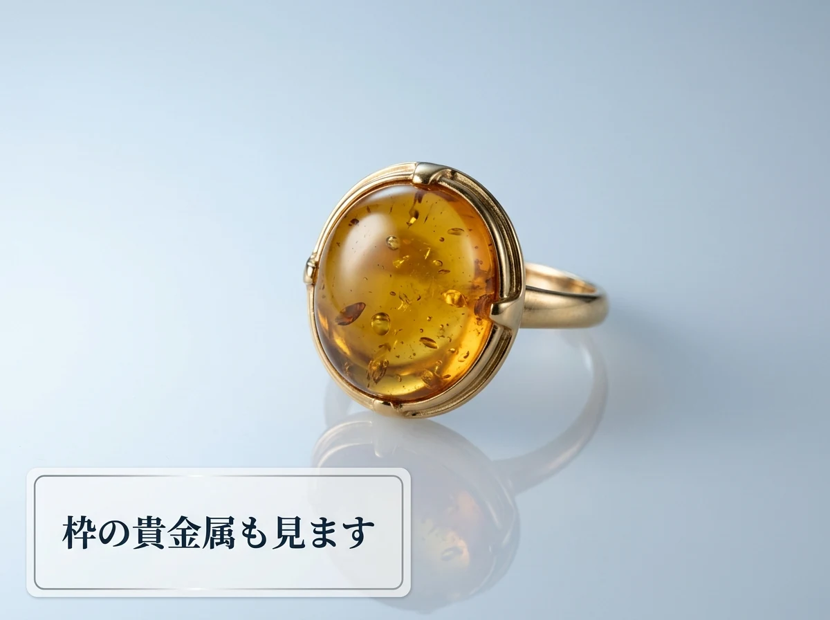 貴金属の枠に留められた琥珀のリングを光沢のある面に置いた写真